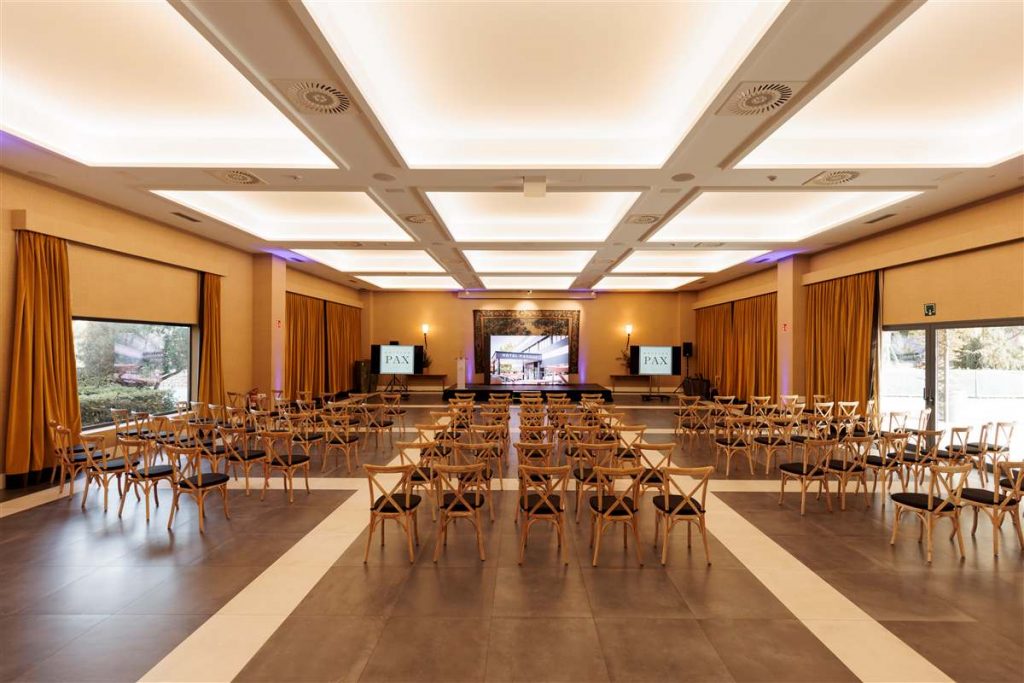 Salón de eventos del Hotel PAX Guadalajara con sillas en formato teatro y pantallas