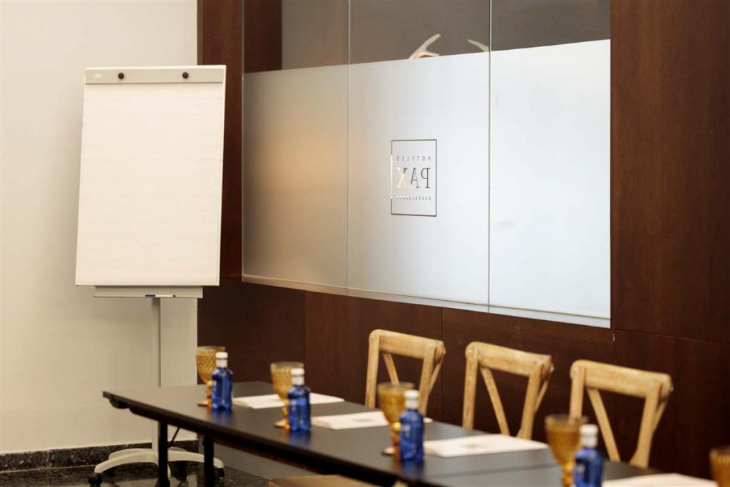 Sala de reuniones del Hotel PAX Guadalajara con rotafolio y mesas preparadas